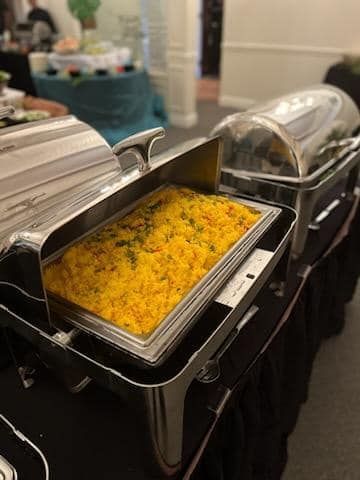 Buffet trays with yellow rice or casserole served in a chafing dish at an indoor event