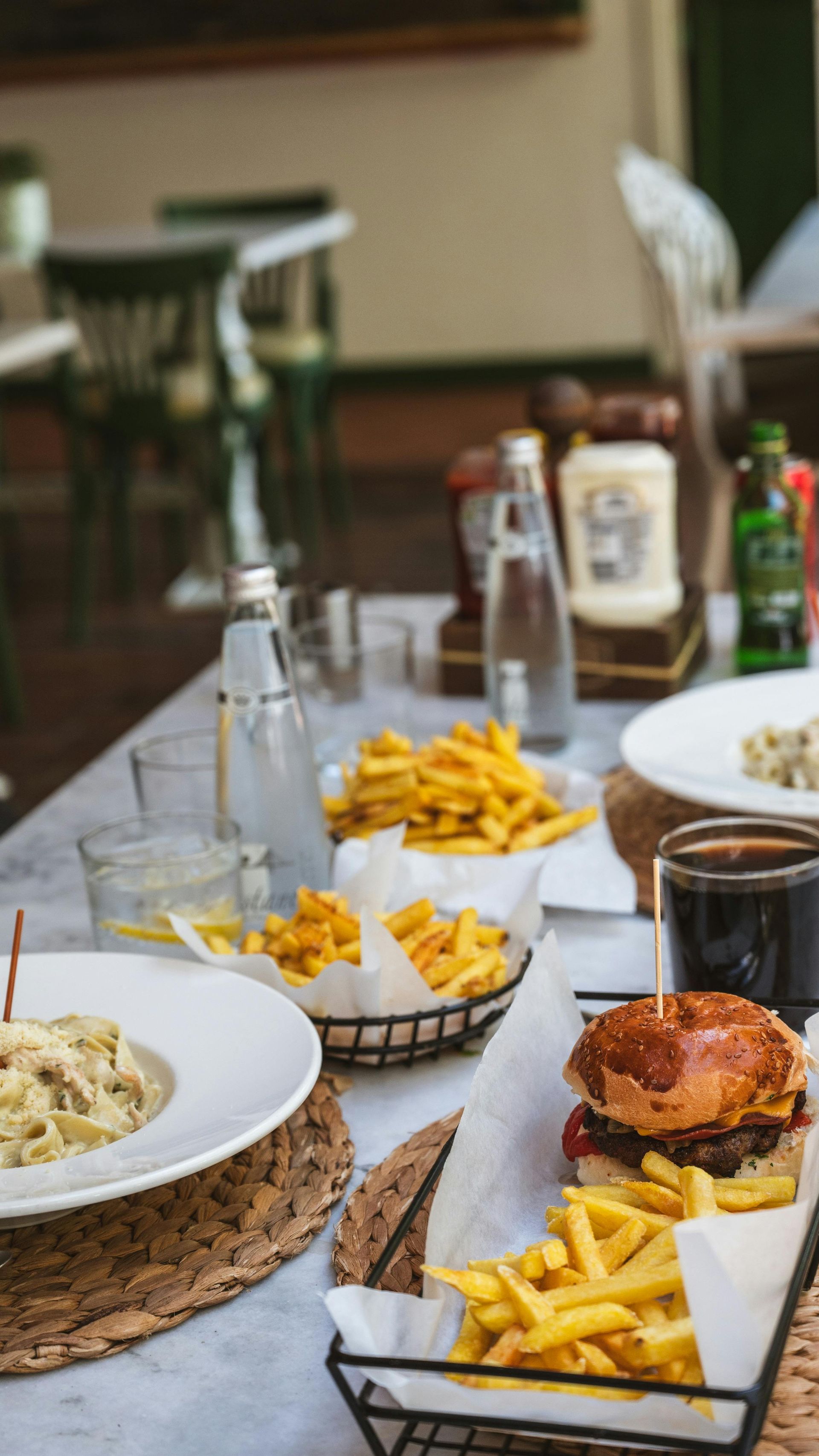 Table with burgers, fries, and drinks on a restaurant table setting