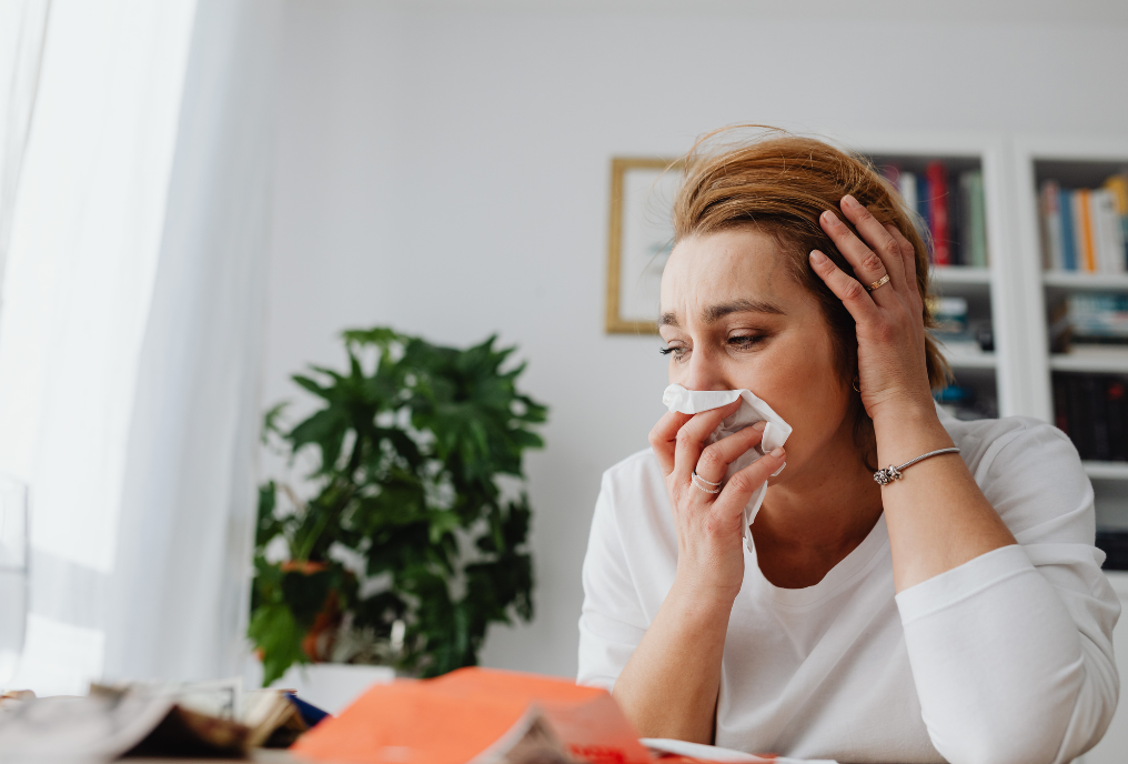 An image of a woman suffering from allergy symptoms, trying to determine what is causing them.