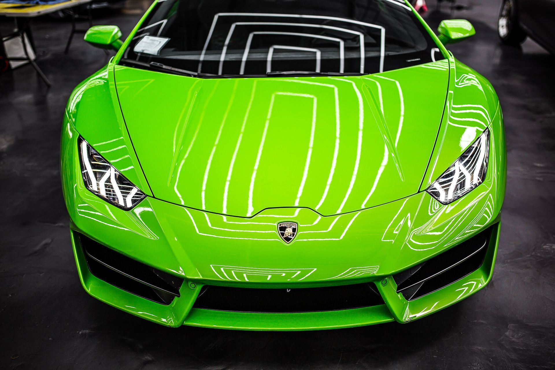 Bright green sports car viewed from the front in a dark showroom