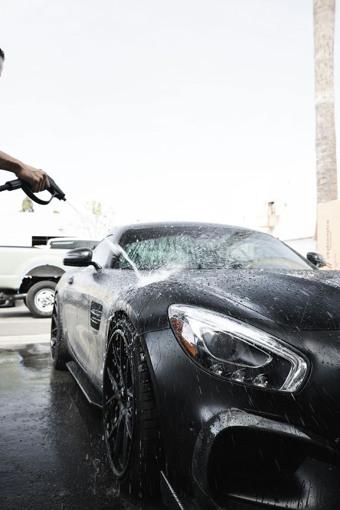 Man cleaning snow and foam off the back of a white pickup truck outdoors