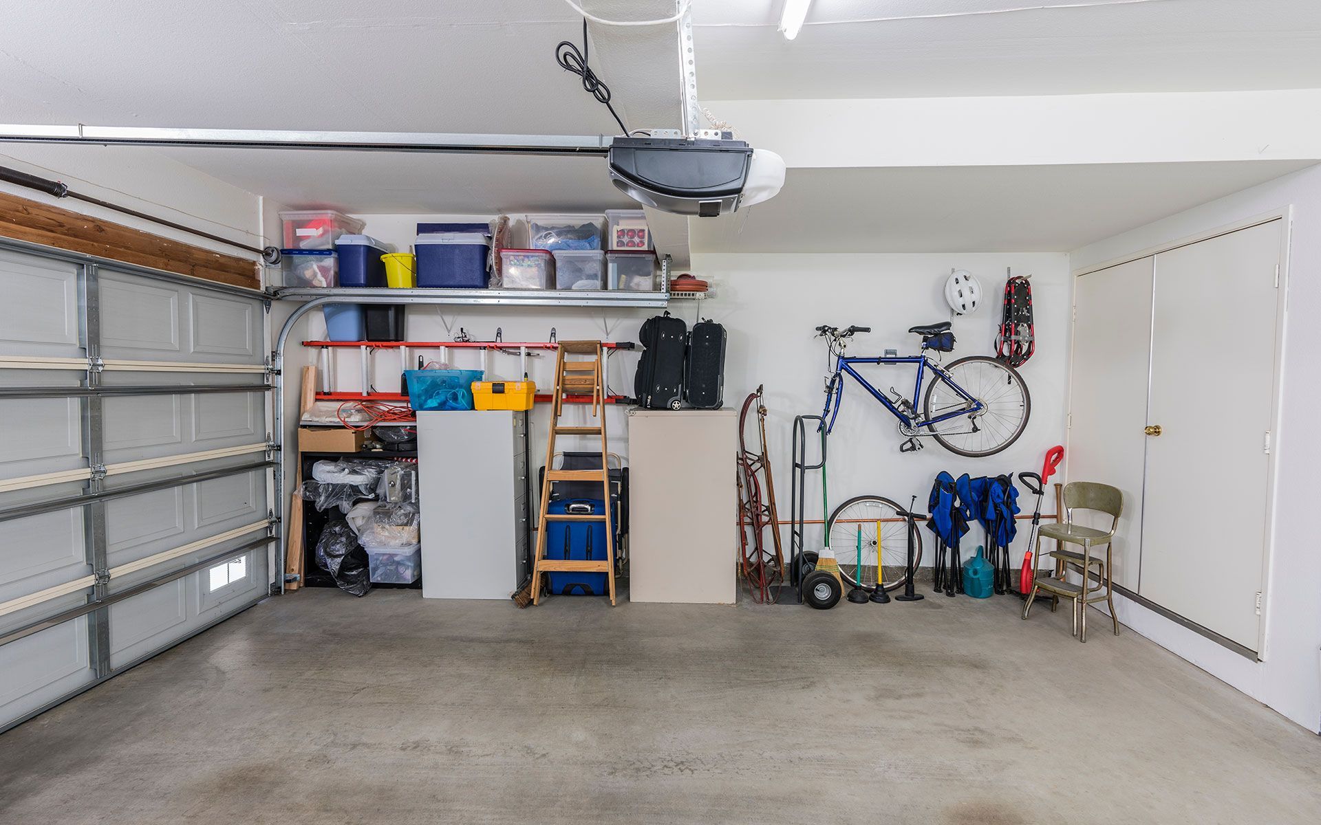 An empty garage with a bicycle hanging on the wall.