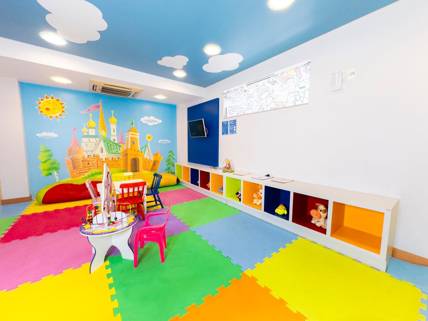 Uma sala de jogos colorida com uma pintura de castelo na parede.