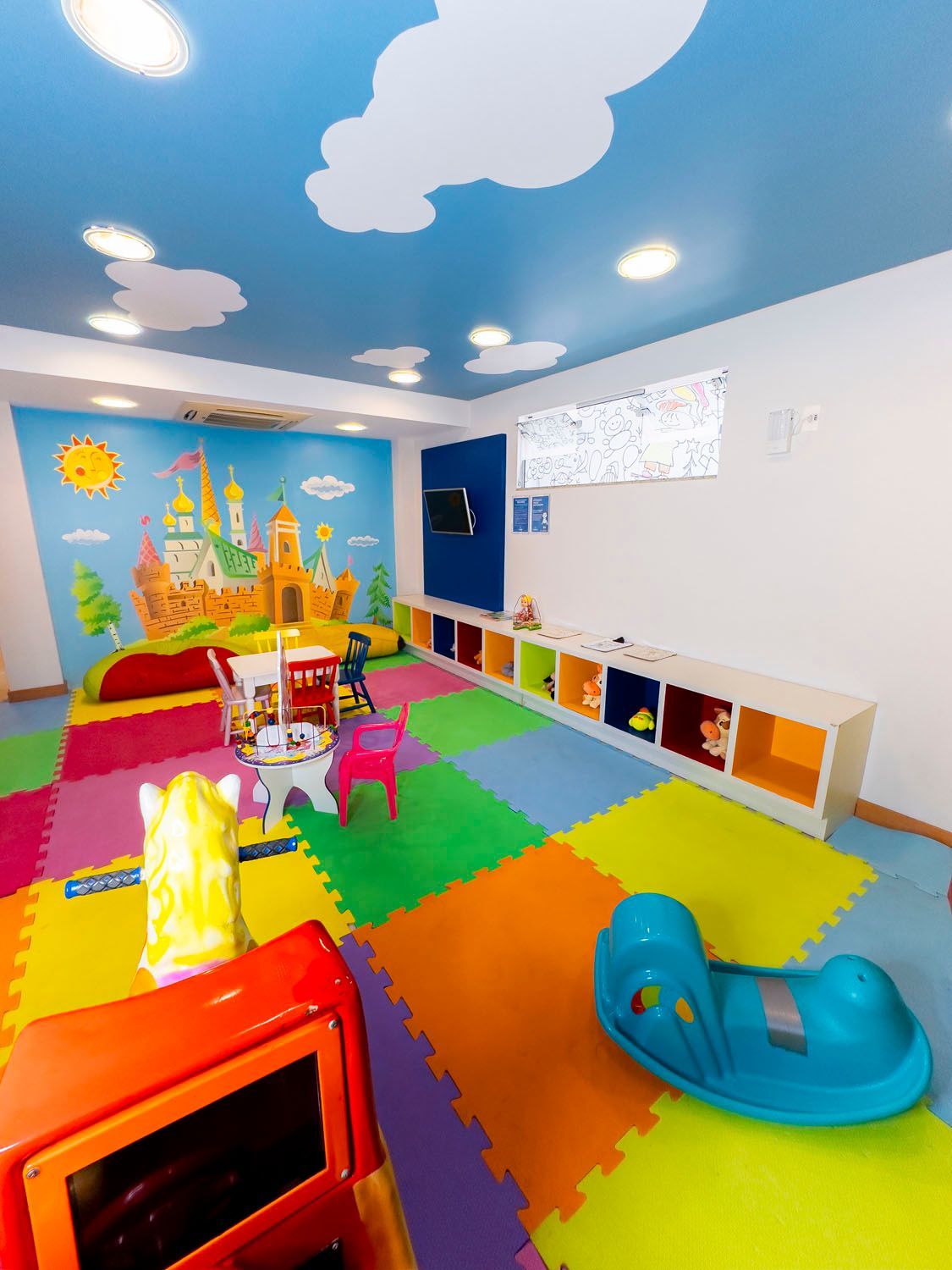 Uma sala de jogos colorida com uma pintura de castelo na parede.