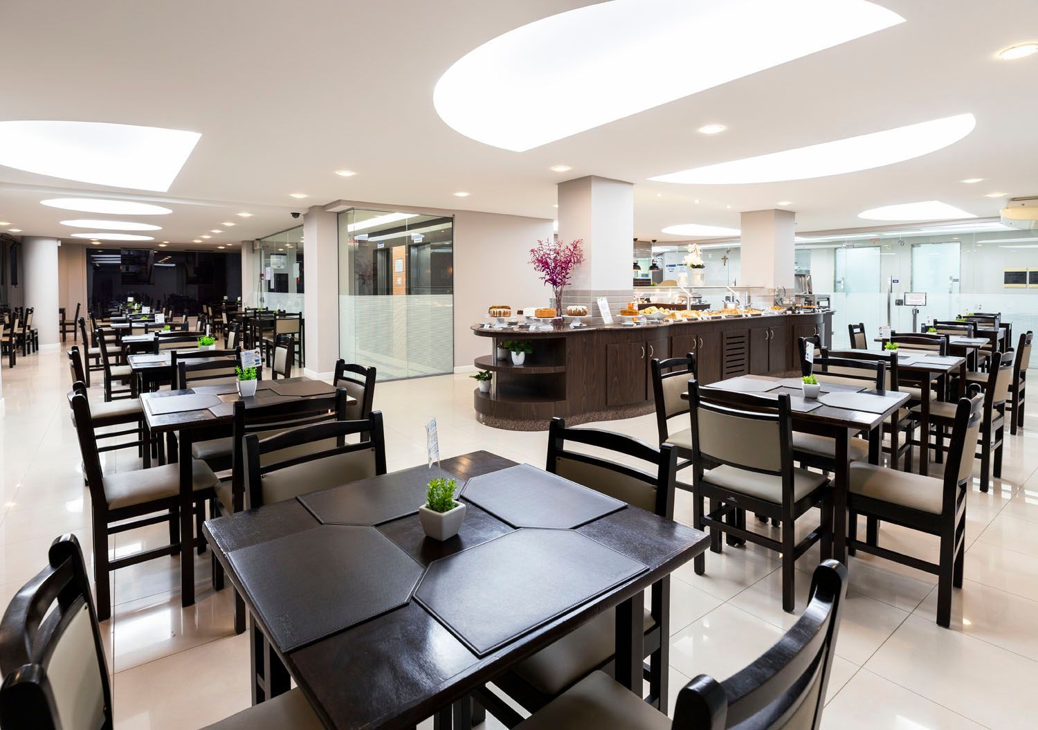Um restaurante com mesas e cadeiras e um buffet.