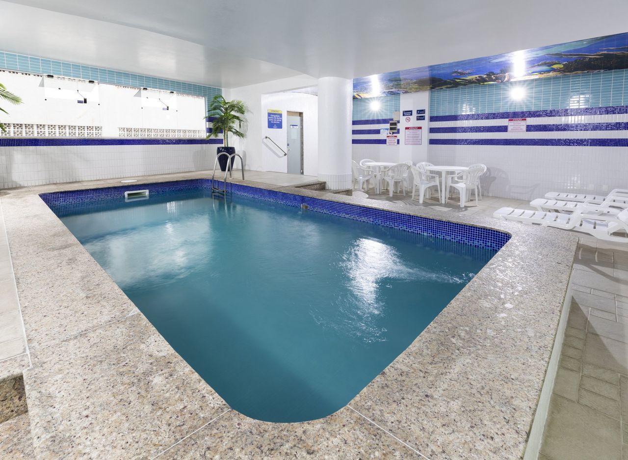 Uma grande piscina coberta com mesas e cadeiras ao redor