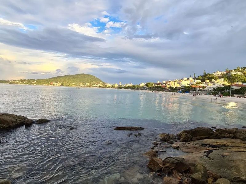 Um grande corpo de água com uma praia ao fundo e uma cidade ao longe.