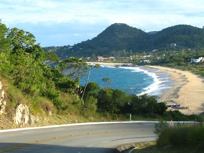 Uma estrada que vai para uma praia com montanhas ao fundo