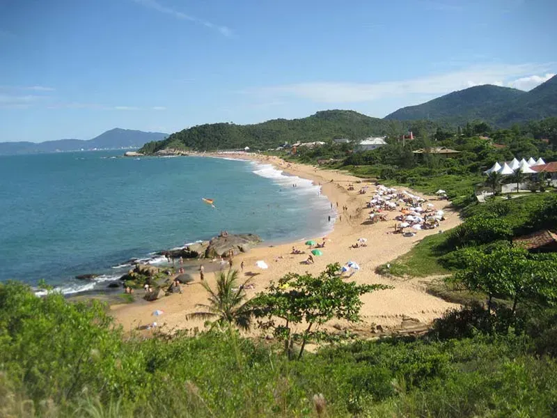 Uma praia com muitas pessoas e montanhas ao fundo