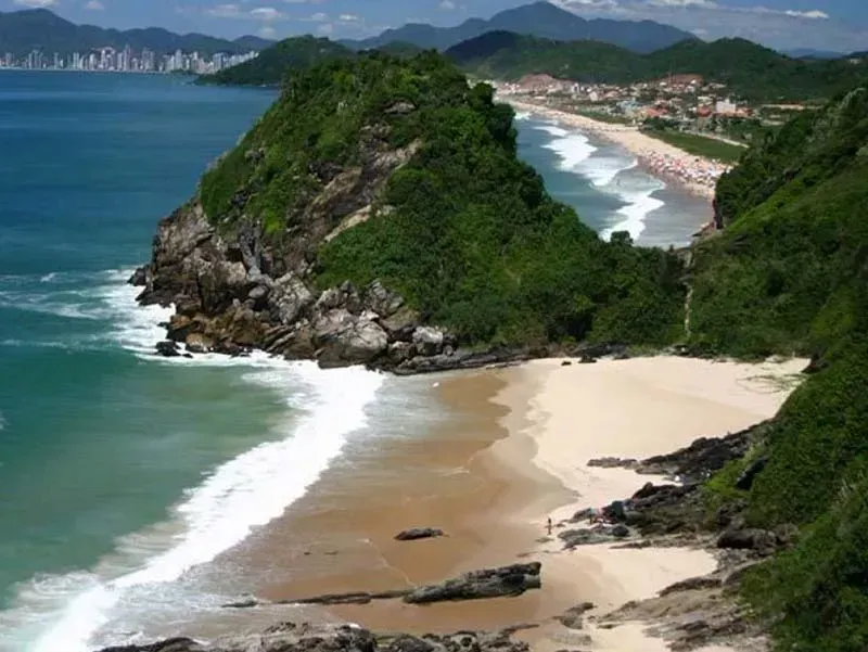 Um penhasco com vista para uma praia com montanhas ao fundo