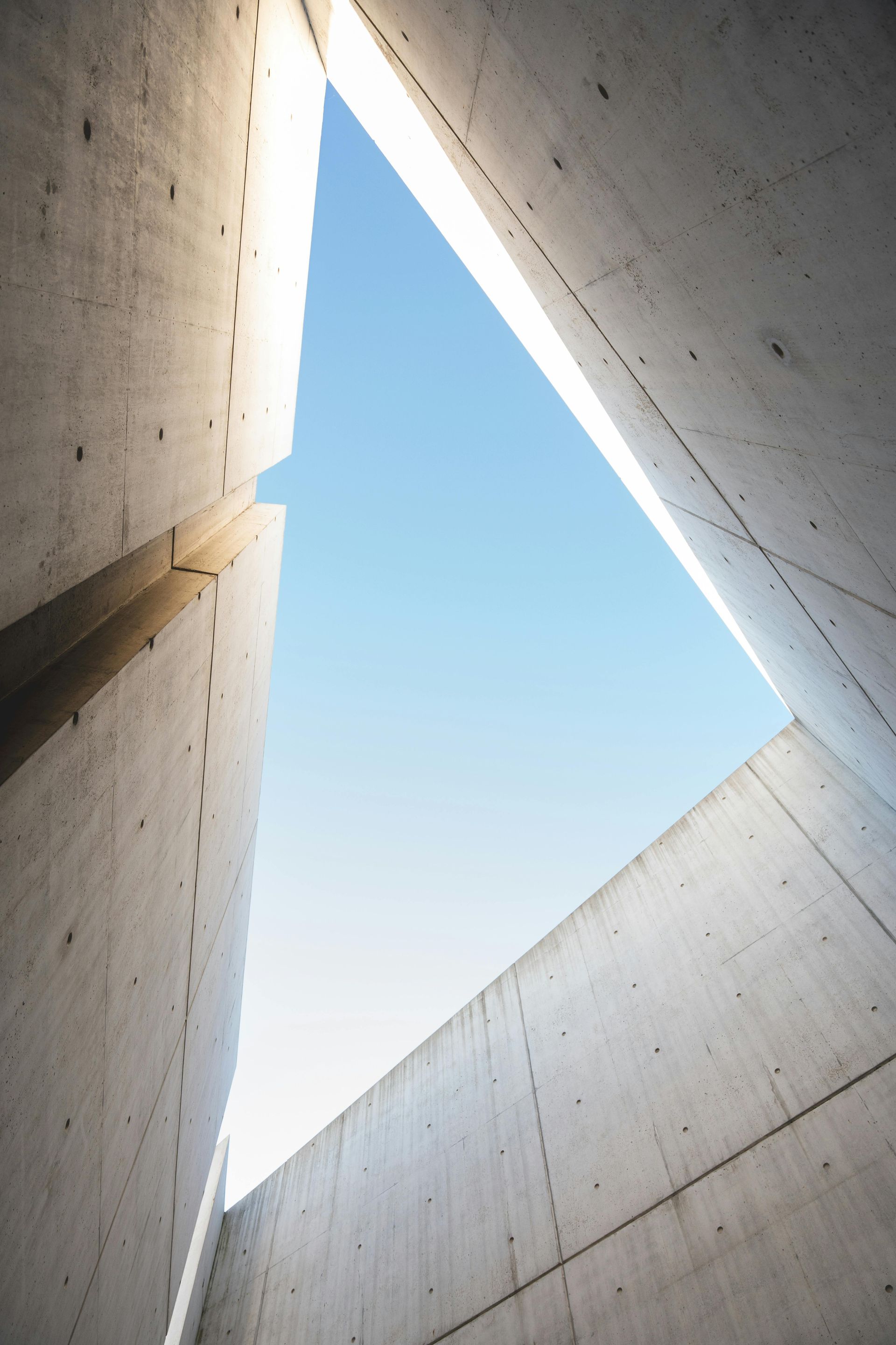 Triangle of blue sky framed by tall concrete walls with textured surfaces
