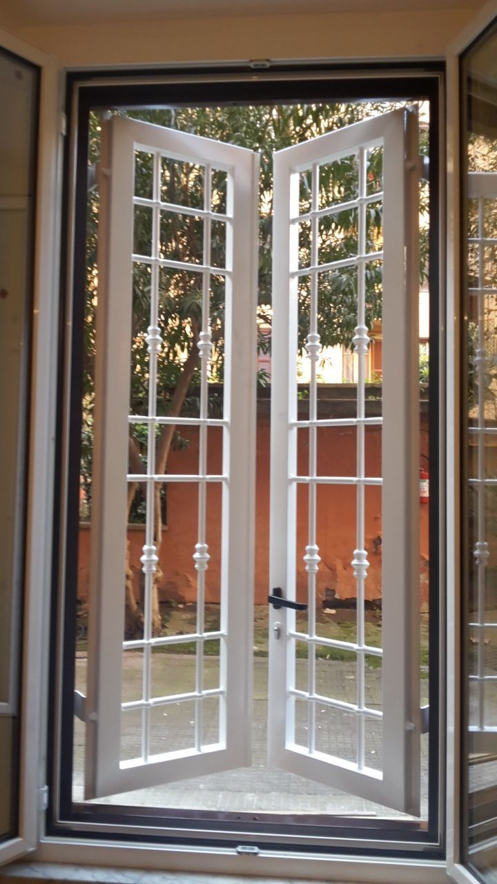 Porte finestre aperte con cornici bianche, che si affacciano su un patio e una recinzione arancione.