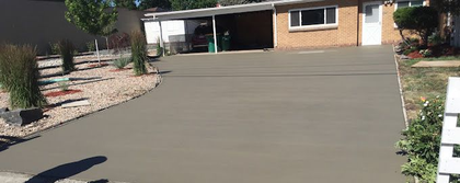 Workers use a red power trowel to smooth fresh concrete on a construction site.