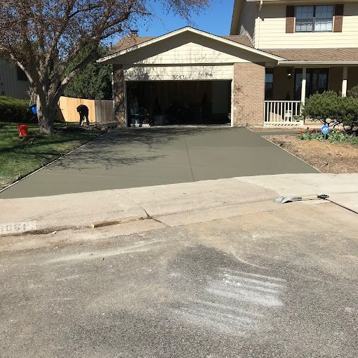 Suburban house with a freshly poured concrete driveway and open garage in front.
