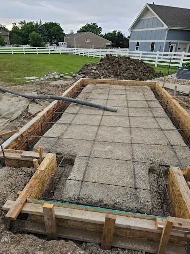 Concrete foundation form with rebar and wooden framing at a residential construction site