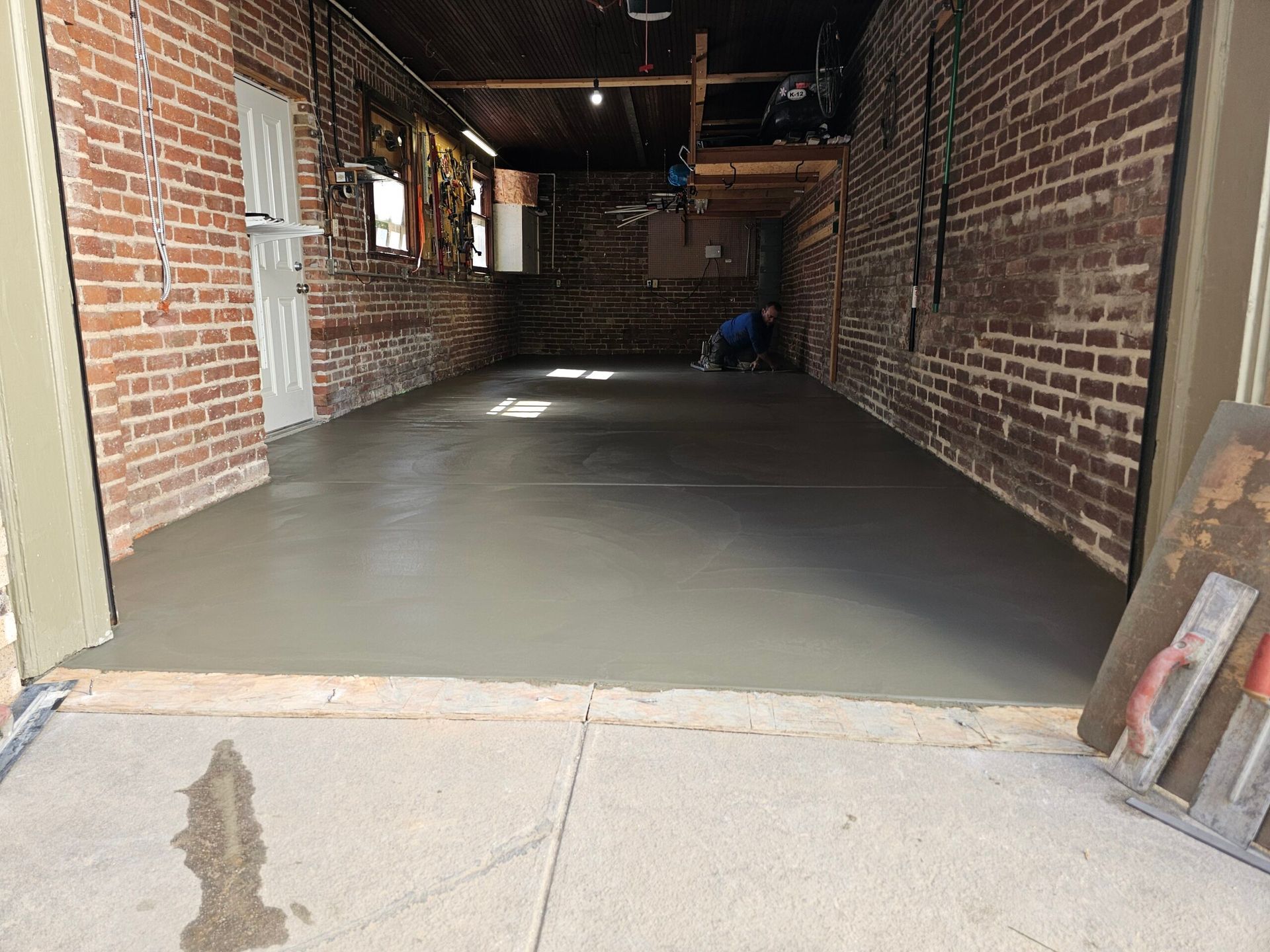 Brick alleyway with a freshly poured concrete floor and an opening to the street at the far end