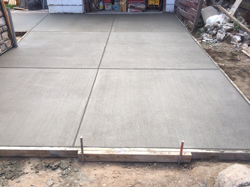 Concrete driveway slab with expansion joints and wooden form at the edge of a garage