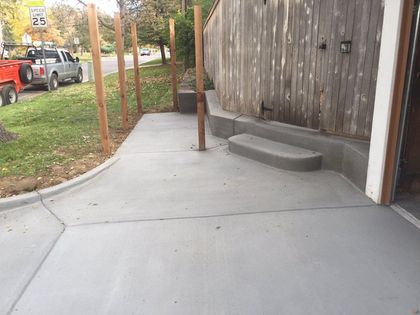 Concrete backyard patio with built-in raised seating and steps beside a wooden fence