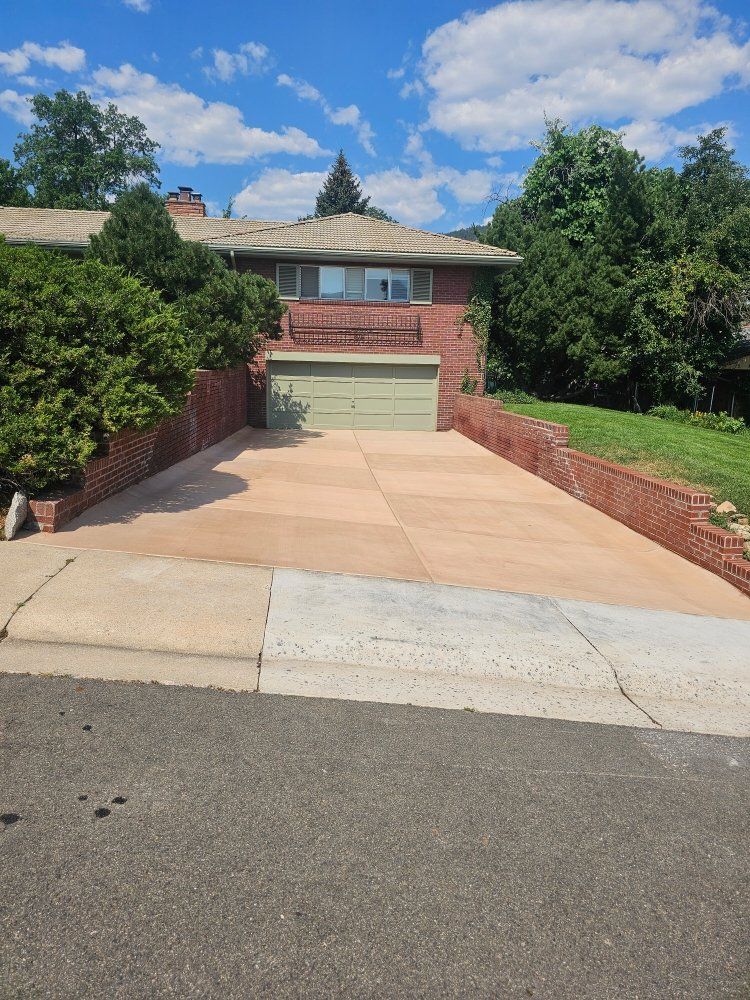 Brick house with green garage door and sloped concrete driveway under a blue sky