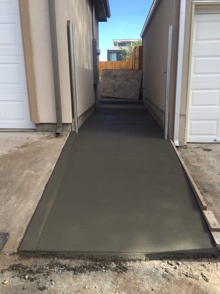 Fresh concrete walkway between two buildings leading to a fenced area outdoors
