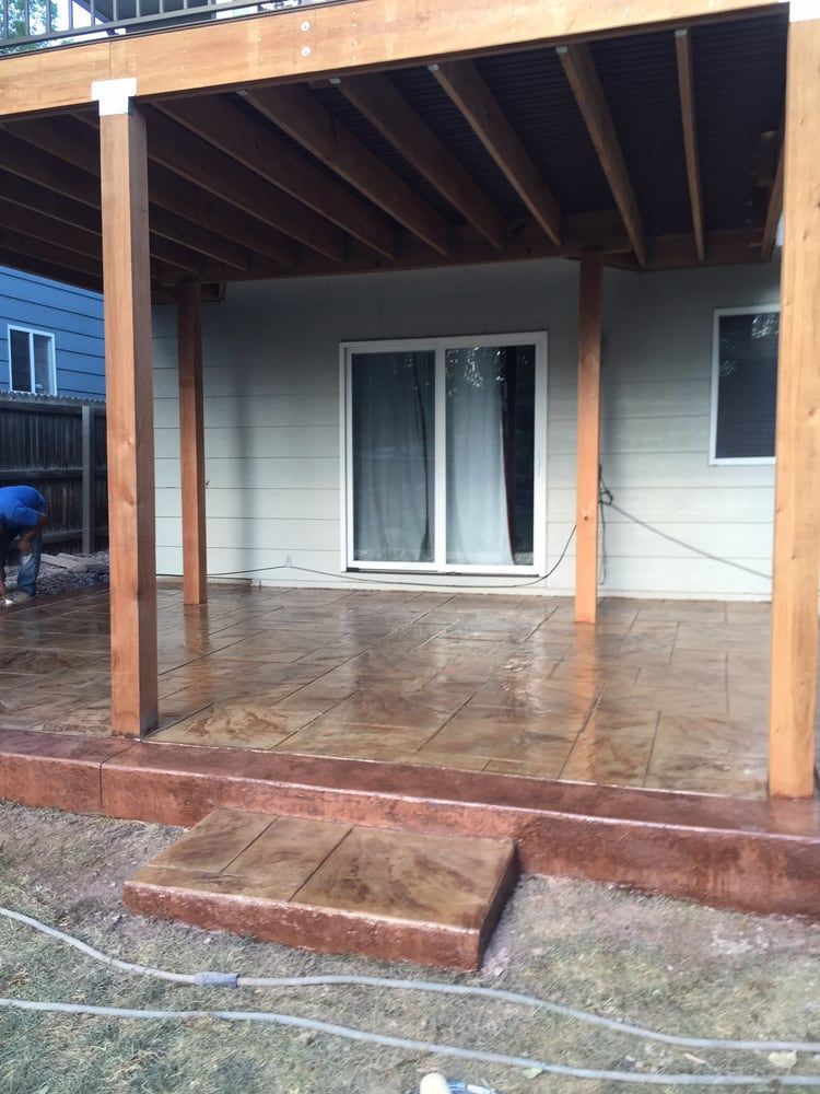 Covered wooden porch with wet deck, steps, and sliding glass door on a small house