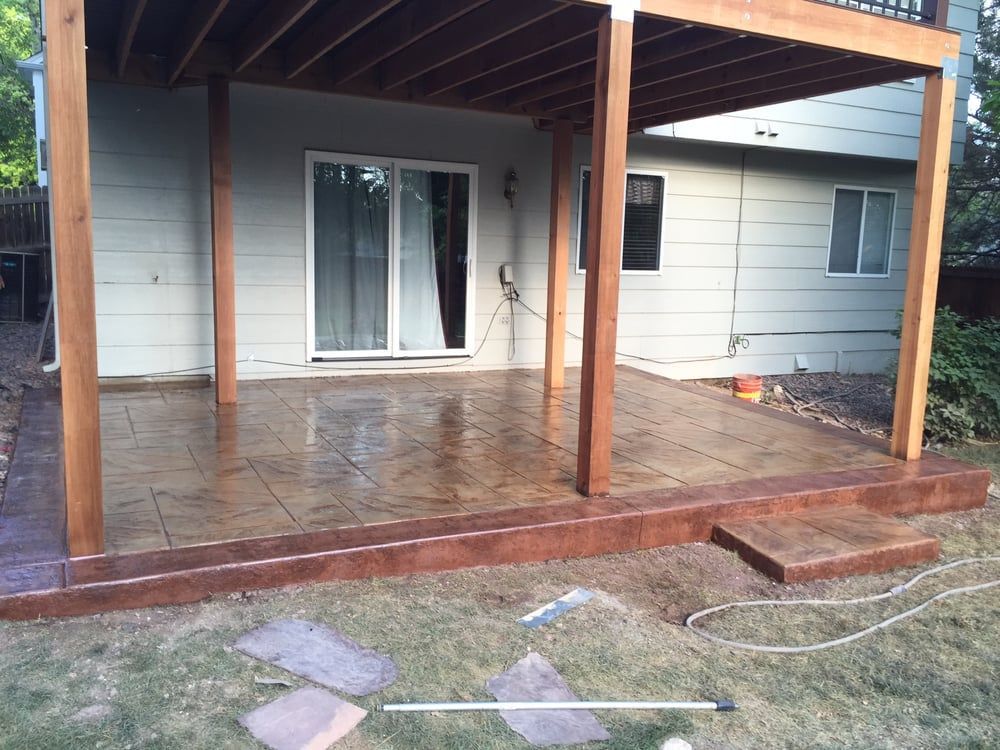 Covered patio with wet brick floor, sliding glass door, and a small grassy yard with stepping stones