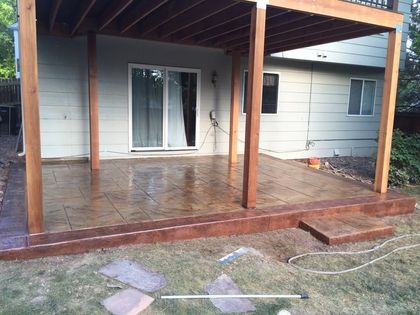 Covered porch with wet tiled floor, wooden posts, sliding glass door, and a patchy grass yard.