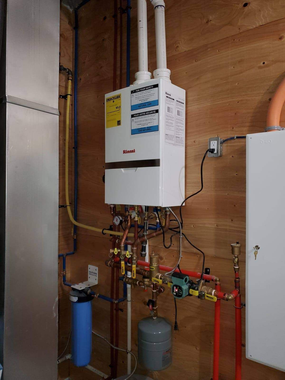 a white water heater is hanging on a wooden wall .