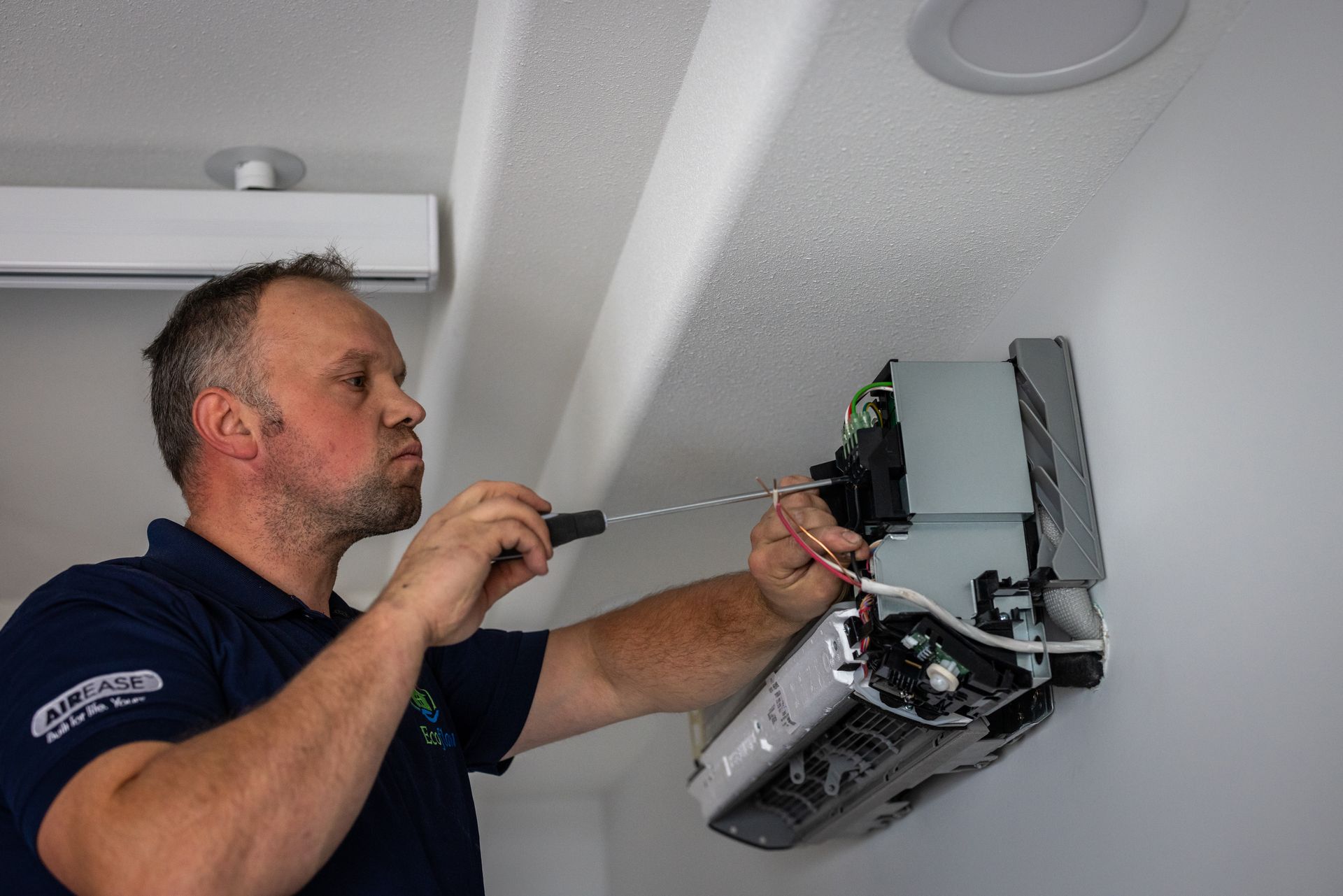 A man is working on a heater hanging from the ceiling.