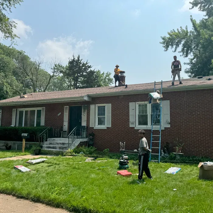 Roofing workers on a house. Men on the roof and lawn, sunny day.