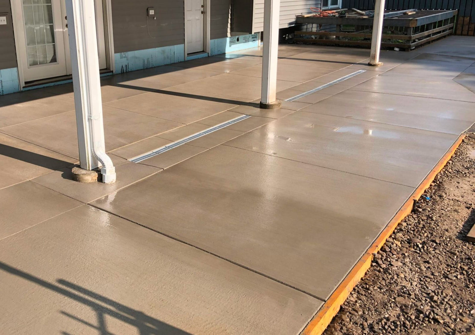 Newly poured concrete patio with two white support columns.