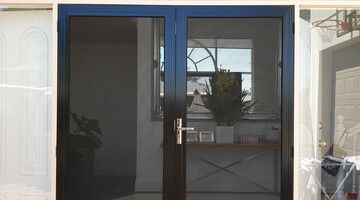 A black screen door is sitting in a room next to a window.