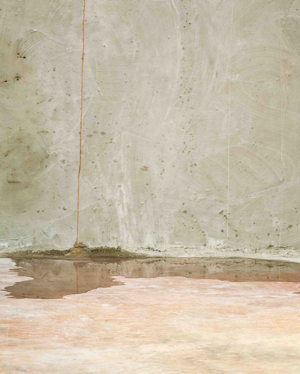 Concrete wall with a water puddle on the floor.
