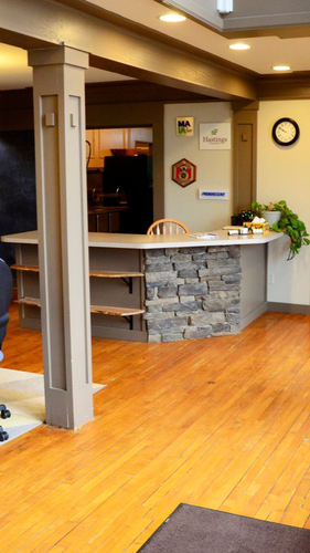 Reception desk with stone facade and wood shelves, wood flooring, and clock on wall.