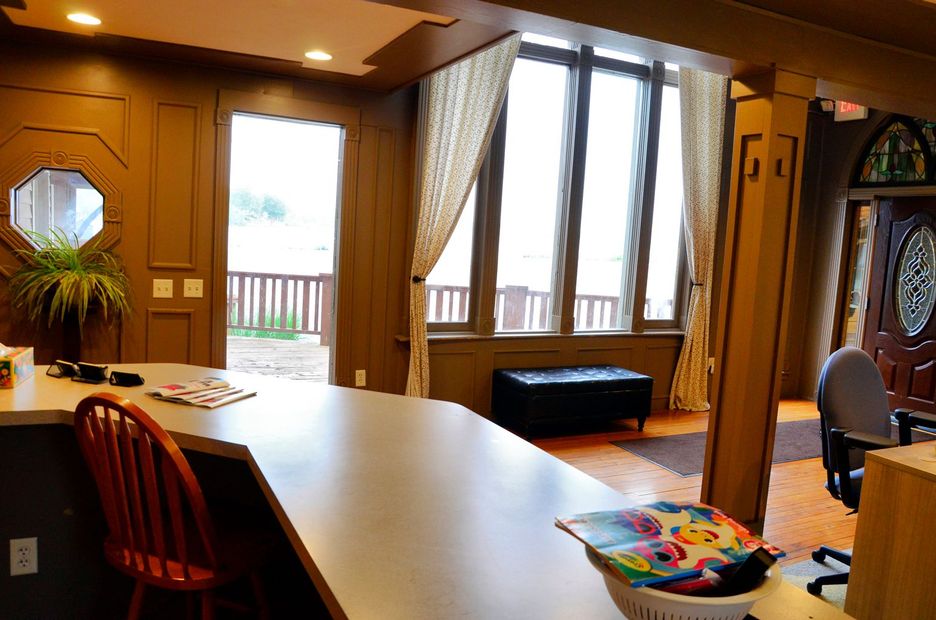 Interior with counter, open door to deck, large windows with curtains, and dark wood paneling.