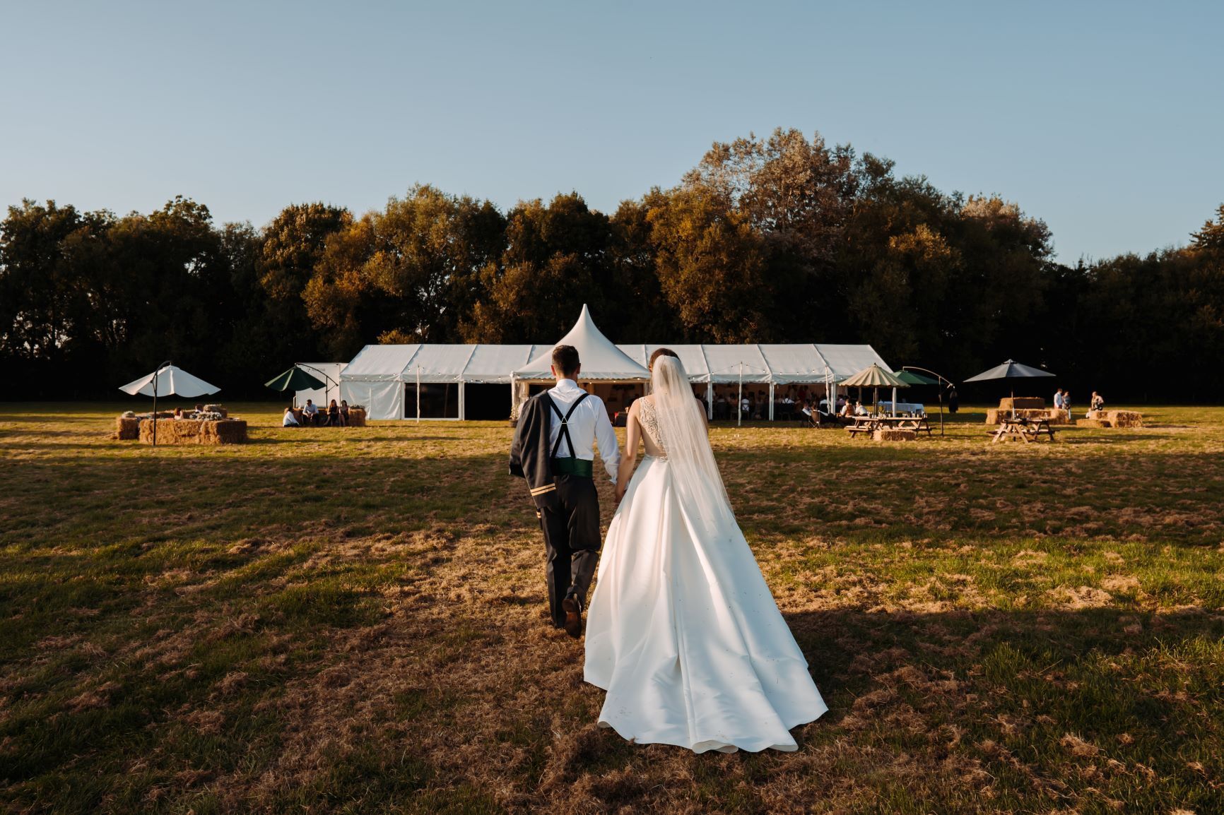 A married couple pose in front of their beautiful wedding marquee