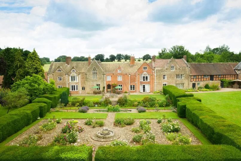 An aerial view of a large house with a garden in front of it.