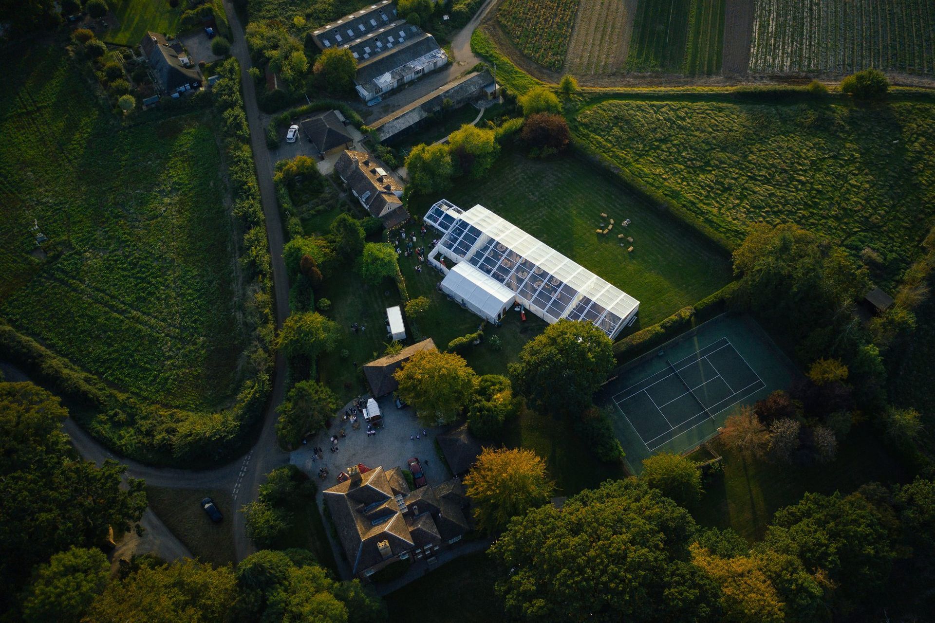 An aerial view of a marquee in the middle of a field surrounded by trees.