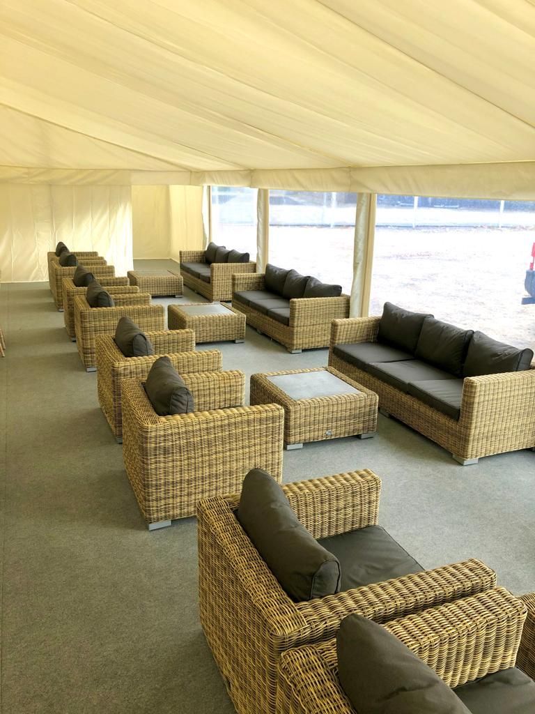 A row of wicker chairs and couches in a marquee