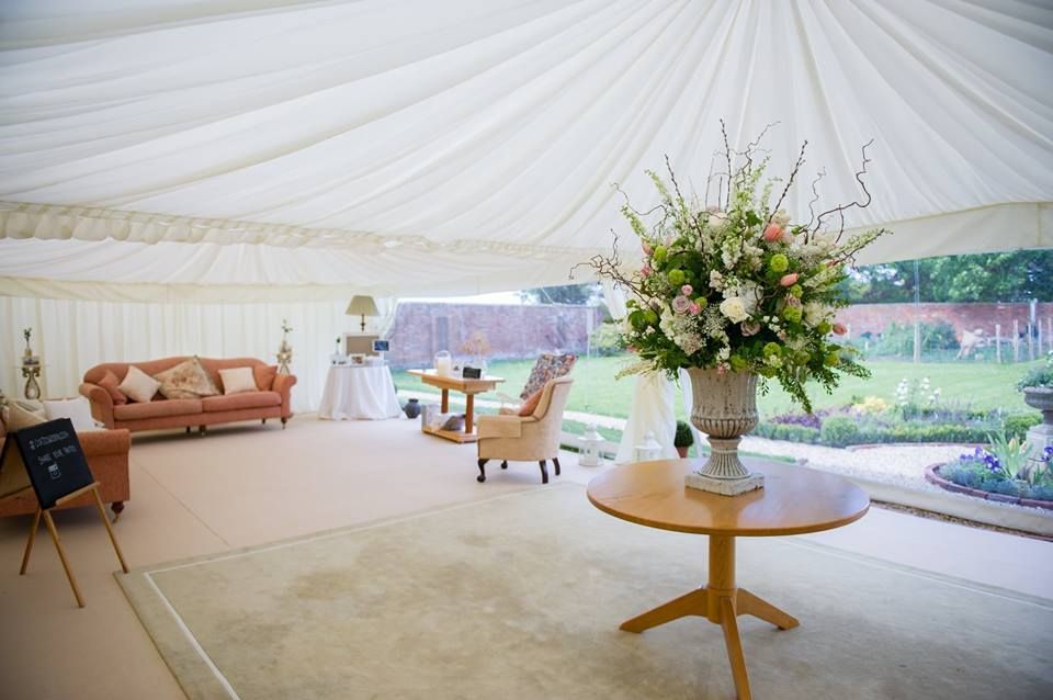A table with a vase of flowers on it in a large marquee