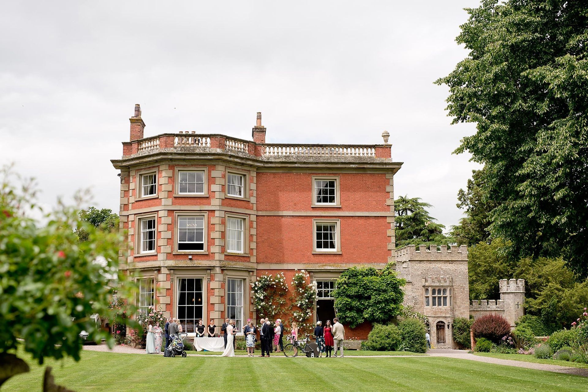 A group of people are standing in front of a large red brick house.