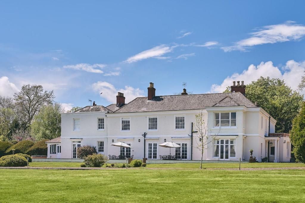 A large white house is sitting on top of a lush green field.