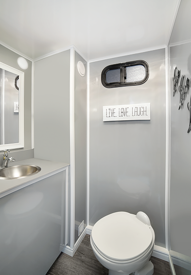 Compact bathroom with toilet, sink, mirror, and gray walls