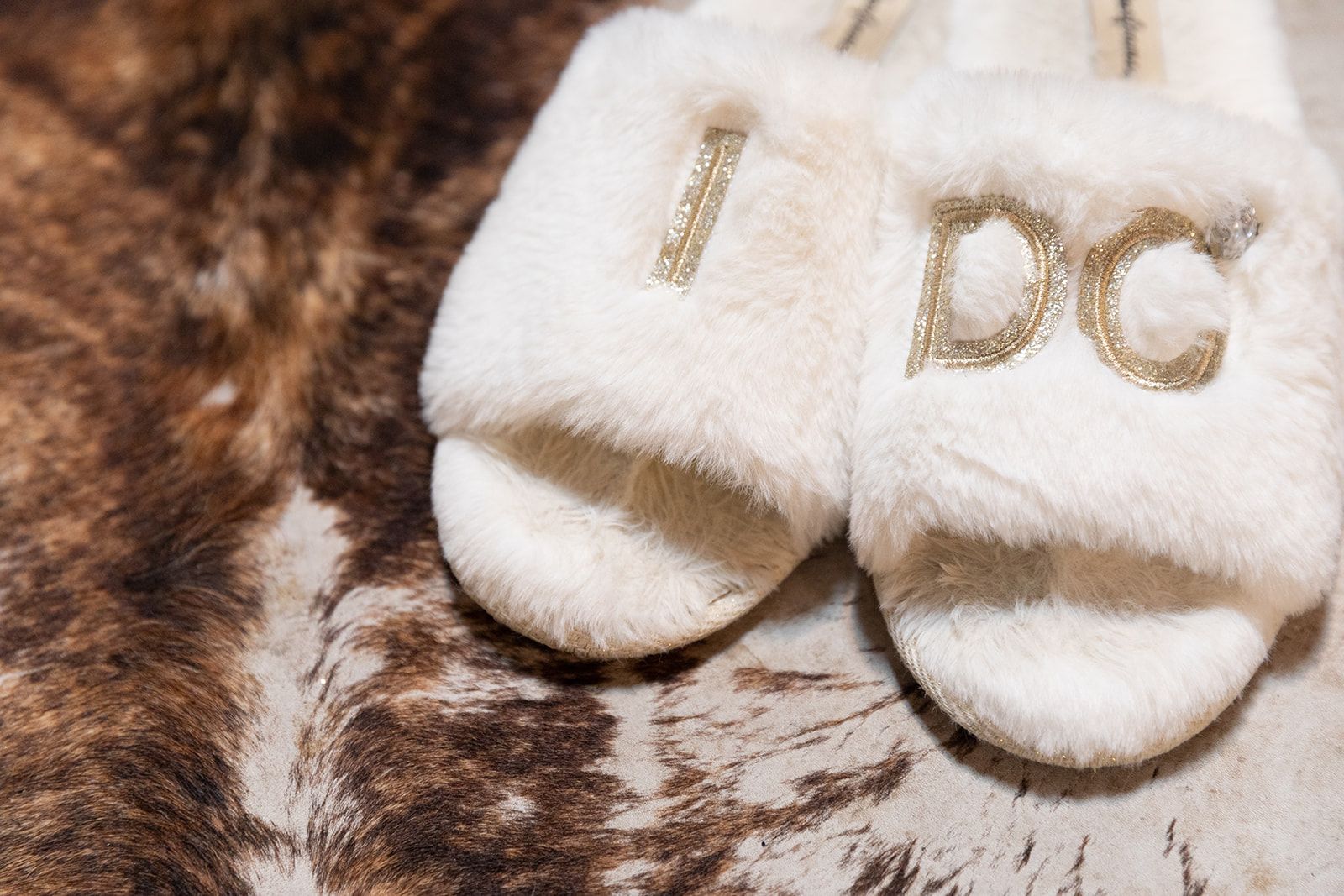 White baby socks with gold “D G” lettering on a brown fur blanket.