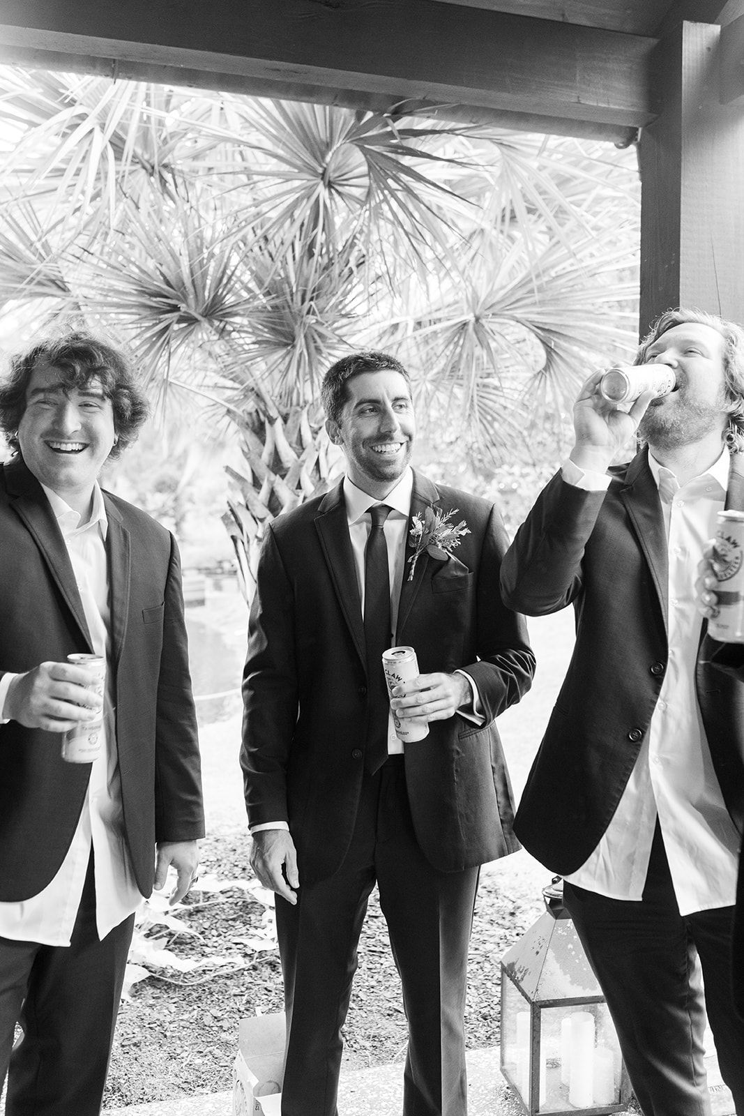 Three men in suits standing outdoors, smiling and drinking at a celebration.
