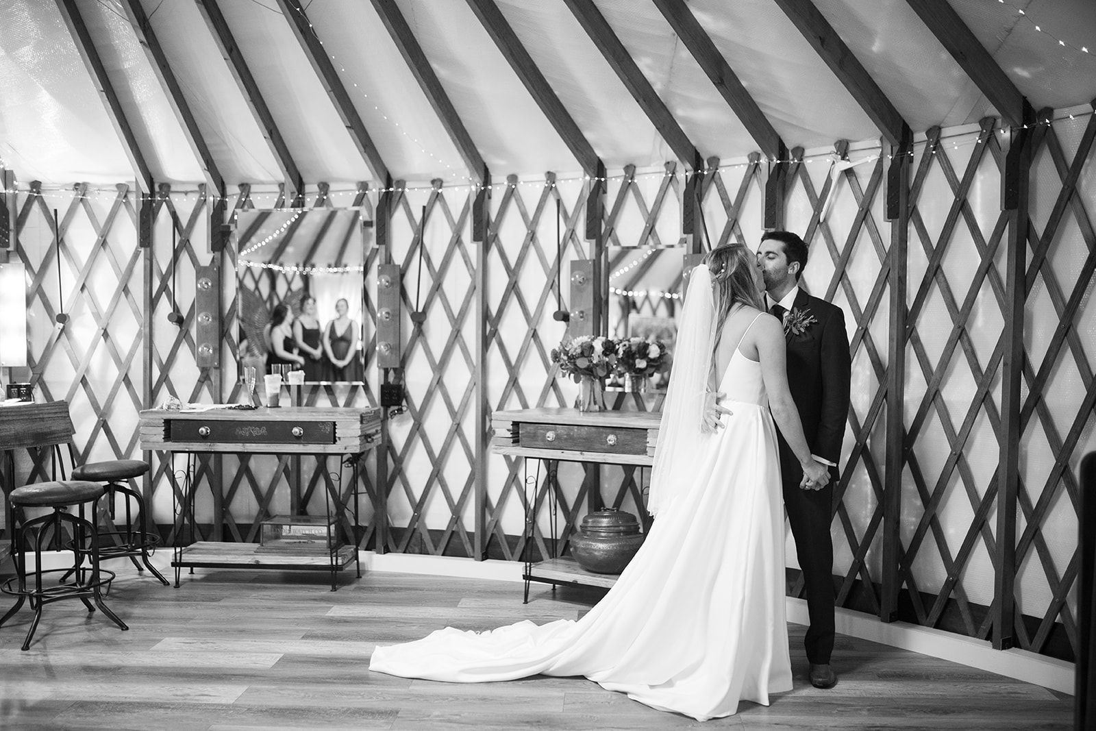 Bride and groom standing together in a decorated tent, bride in a long white gown and veil
