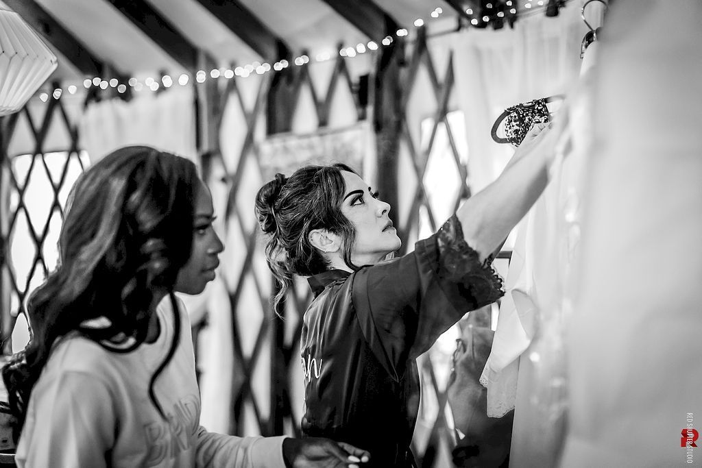 Two people painting a wall at an indoor event, one reaching up with a brush.