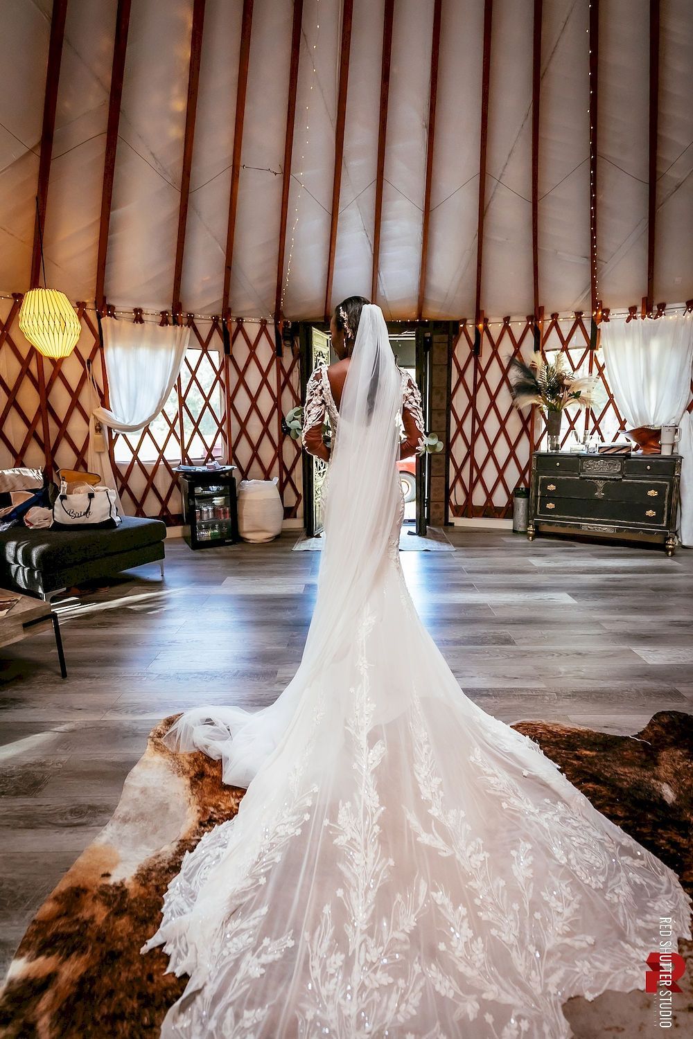 White wedding dress with long train displayed inside a yurt-like tent setting