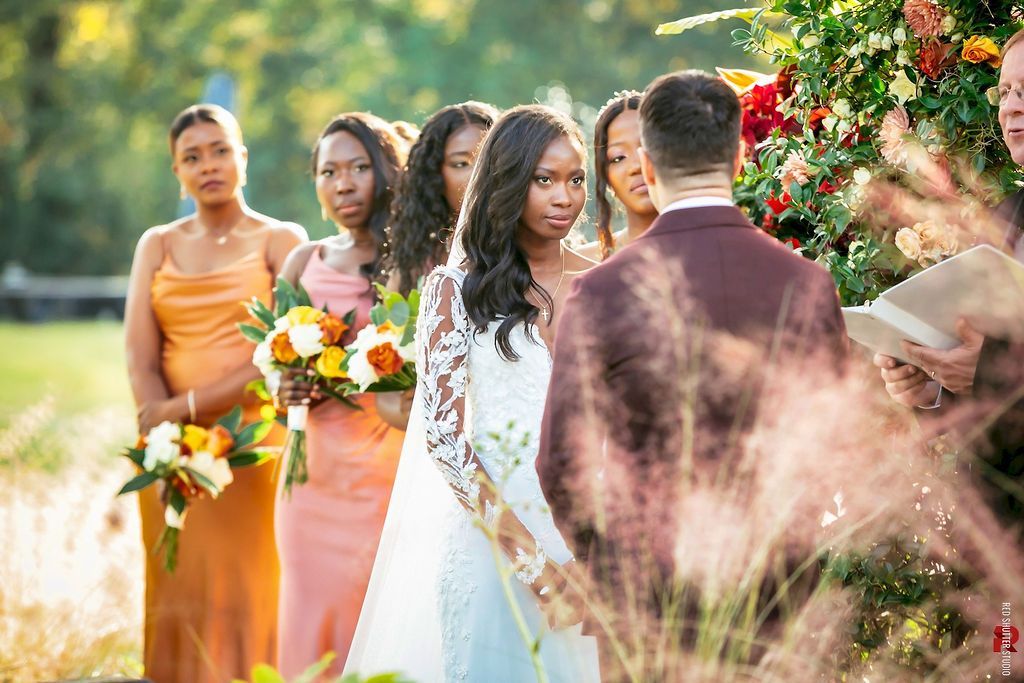 Bride with bridesmaids holding bouquets in a garden wedding ceremony