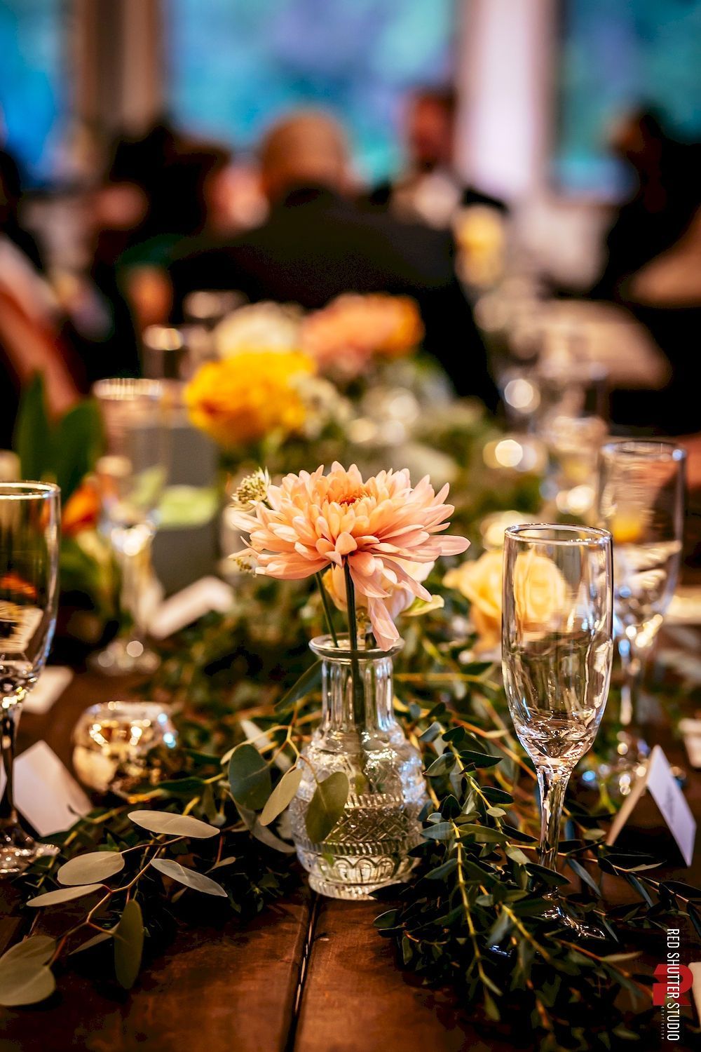 Elegant banquet table with flowers, glassware, and candles in warm, soft lighting